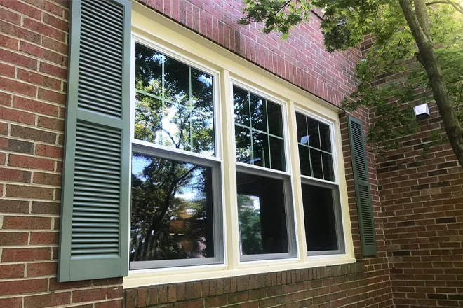 Closeup of new white wood windows in a brick house - Clifton Exteriors, LLC Closeup of new white wood windows in a brick house